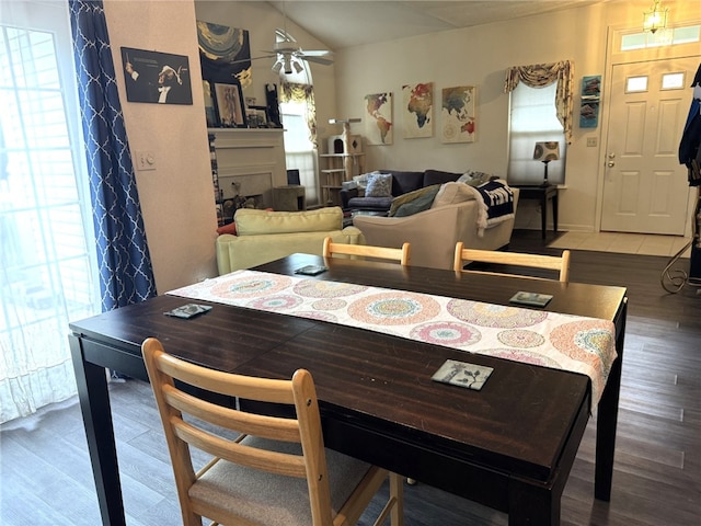 dining area featuring wood finished floors, a ceiling fan, vaulted ceiling, and a fireplace