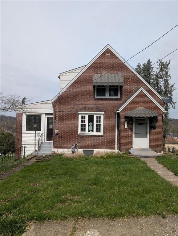 view of front of property featuring entry steps, brick siding, and a front yard