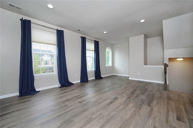 spare room with plenty of natural light, wood finished floors, recessed lighting, and baseboards
