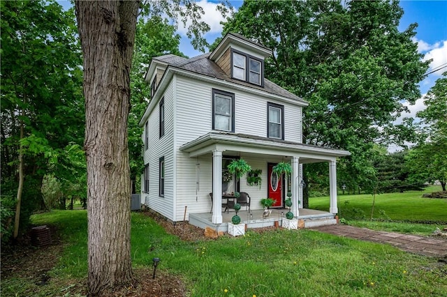 american foursquare style home with a porch, a front lawn, and cooling unit