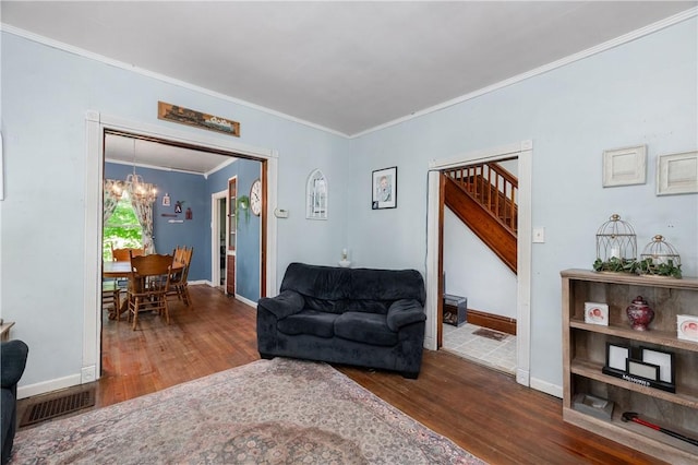 living room featuring wood finished floors, crown molding, a chandelier, baseboards, and stairs
