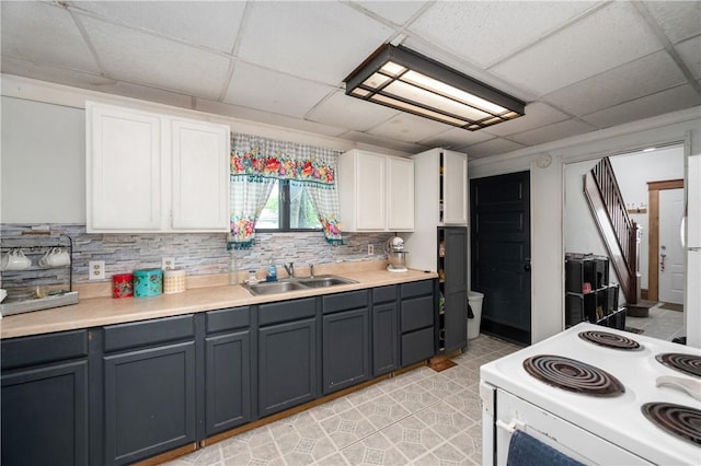 kitchen with white electric range, a sink, a paneled ceiling, white cabinetry, and light countertops