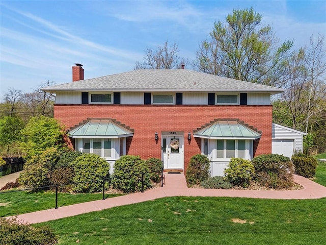 colonial home featuring brick siding, a chimney, a front yard, and a garage