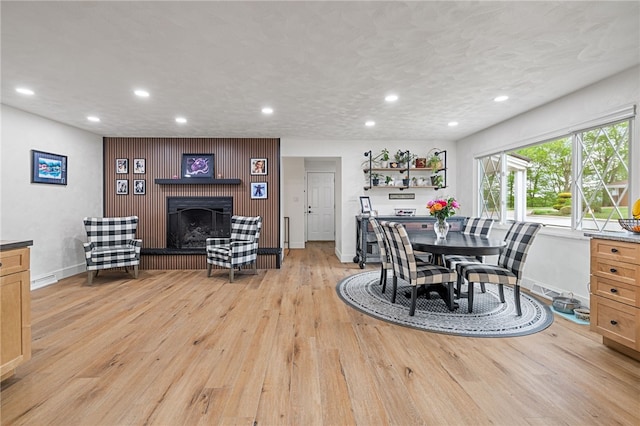 dining area with a brick fireplace, recessed lighting, light wood-type flooring, and baseboards