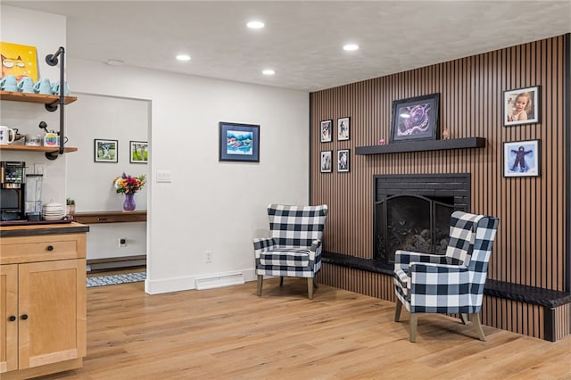 living area featuring light wood finished floors, recessed lighting, a fireplace with raised hearth, and baseboards