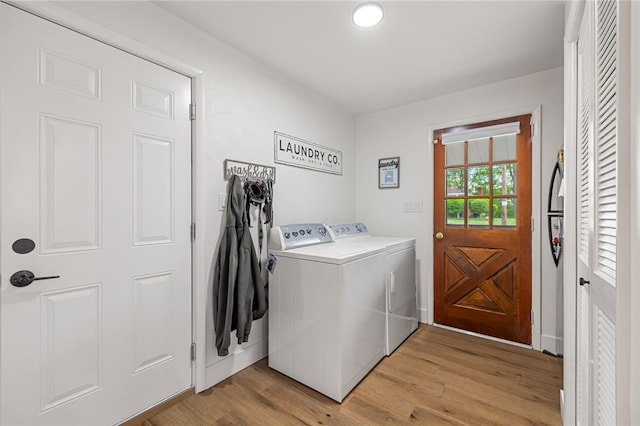 clothes washing area featuring washing machine and clothes dryer and light wood-style floors