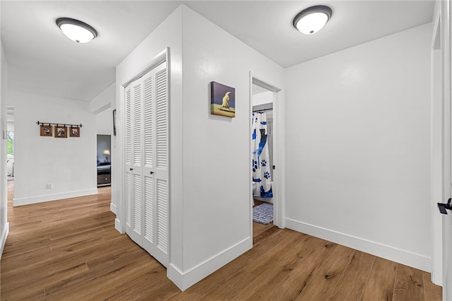 corridor with baseboards and wood finished floors