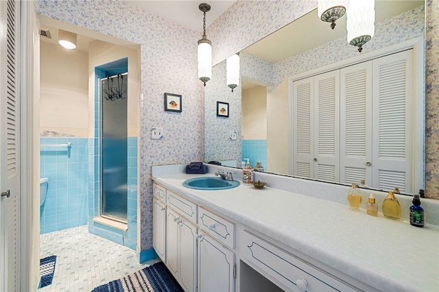 full bath featuring wallpapered walls, vanity, a closet, a tile shower, and tile patterned floors