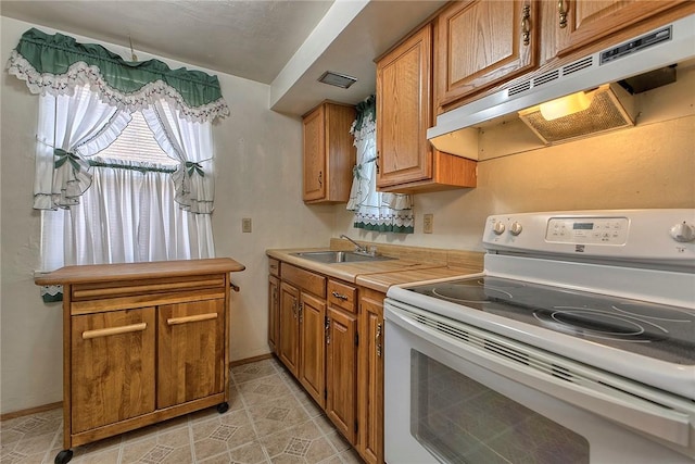 kitchen featuring white electric range oven, under cabinet range hood, a sink, and brown cabinets
