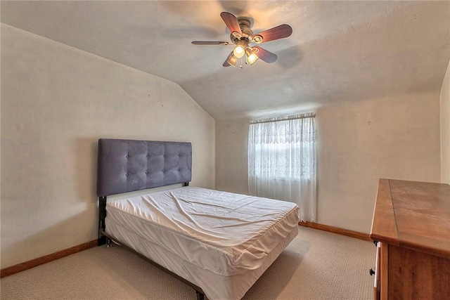 bedroom featuring lofted ceiling, light colored carpet, baseboards, and a ceiling fan