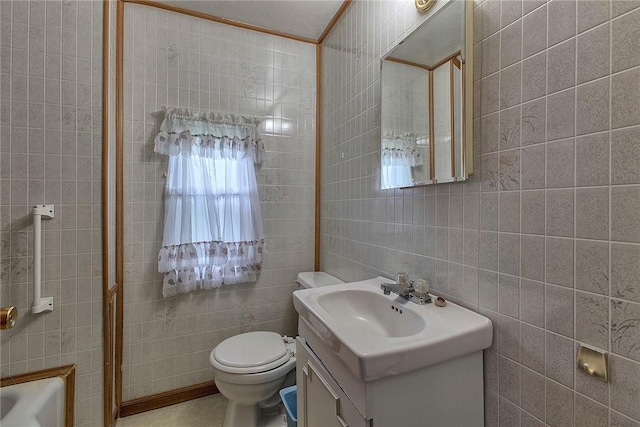 bathroom featuring tile walls, vanity, toilet, and a bath