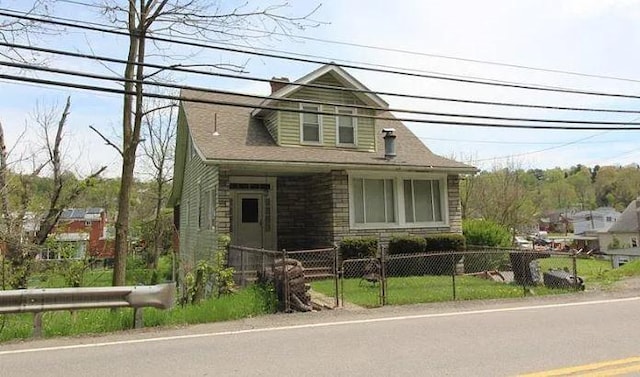 bungalow featuring a fenced front yard and stone siding