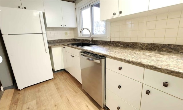 kitchen featuring freestanding refrigerator, dishwasher, a sink, light wood-style flooring, and white cabinets
