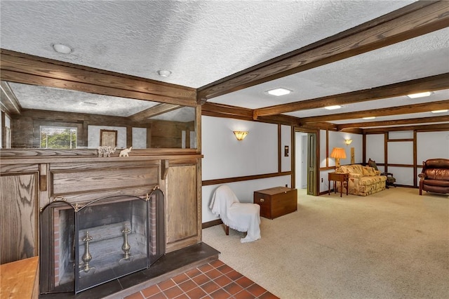 living area with a textured ceiling, beam ceiling, dark colored carpet, a fireplace with raised hearth, and baseboards