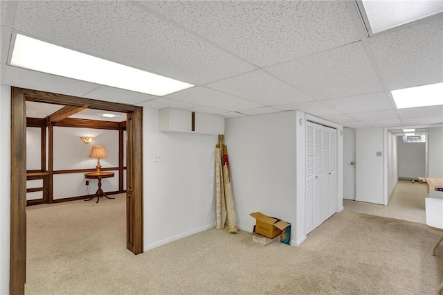 finished below grade area with carpet, a paneled ceiling, and baseboards
