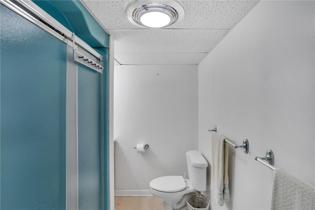 bathroom with toilet and a drop ceiling