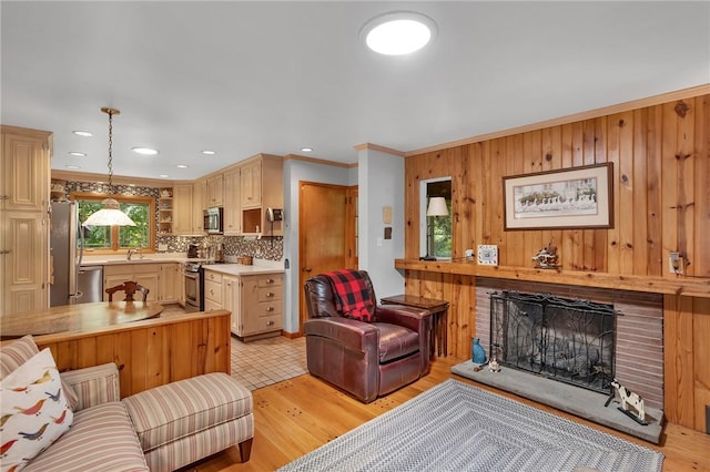 living room featuring a fireplace with raised hearth, wood walls, light wood-style flooring, crown molding, and recessed lighting