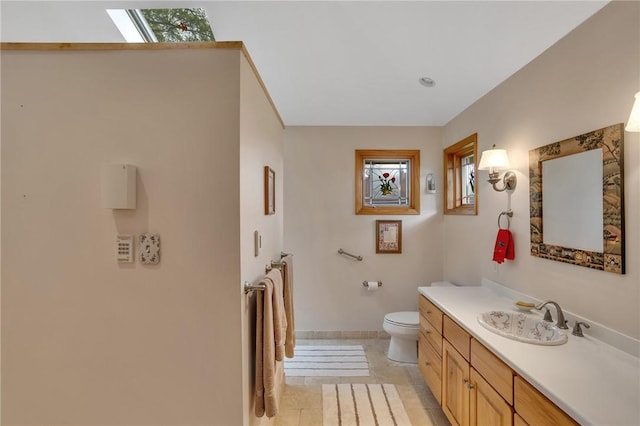 bathroom featuring toilet, vanity, baseboards, and tile patterned floors