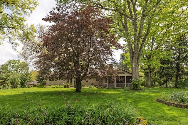view of green lawn with a sunroom