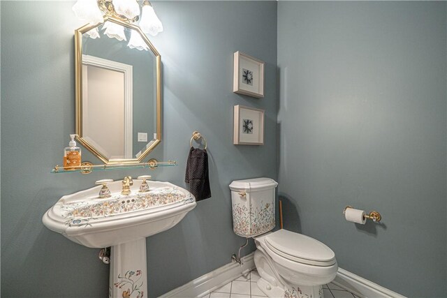 half bath featuring baseboards, toilet, marble look tile flooring, and a chandelier