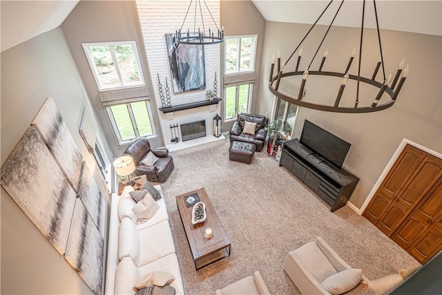 living room with high vaulted ceiling, a chandelier, carpet flooring, a brick fireplace, and baseboards