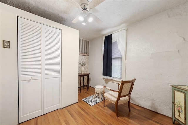 living area featuring light wood-style flooring and a ceiling fan