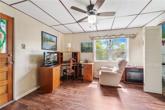office with wood finished floors, a paneled ceiling, ceiling fan, and baseboards