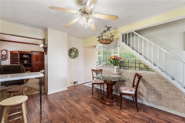 dining room with crown molding, wood finished floors, ceiling fan, baseboards, and stairs