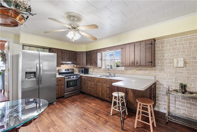 kitchen with appliances with stainless steel finishes, under cabinet range hood, crown molding, a sink, and light countertops