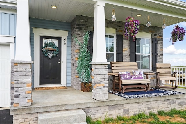 view of exterior entry with a porch and stone siding