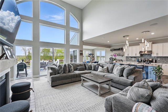 living area featuring light wood-style floors, recessed lighting, a fireplace, and a high ceiling