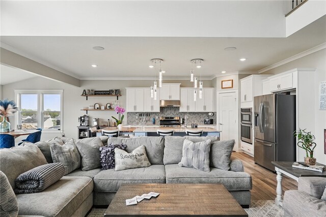 living area with light wood-style floors, crown molding, and recessed lighting