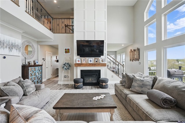 living room with a towering ceiling, stairs, a large fireplace, healthy amount of natural light, and baseboards