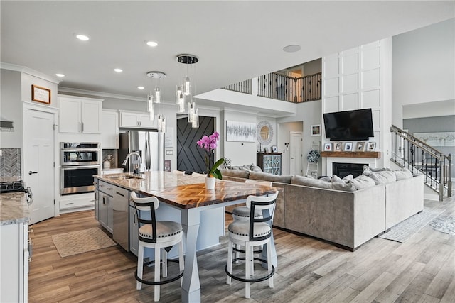 kitchen with stainless steel appliances, a sink, open floor plan, a kitchen breakfast bar, and a center island with sink