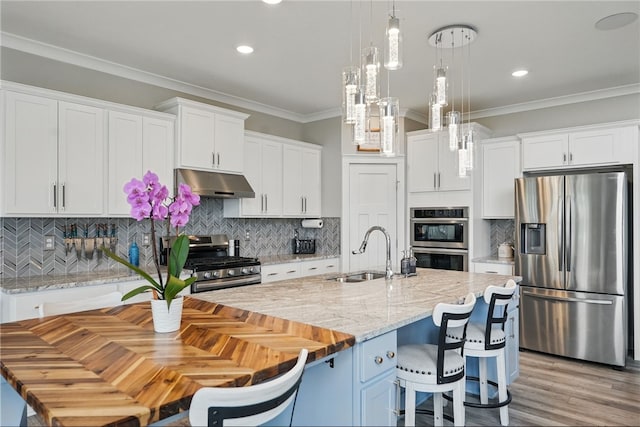 kitchen with stainless steel appliances, a sink, under cabinet range hood, white cabinetry, and ornamental molding