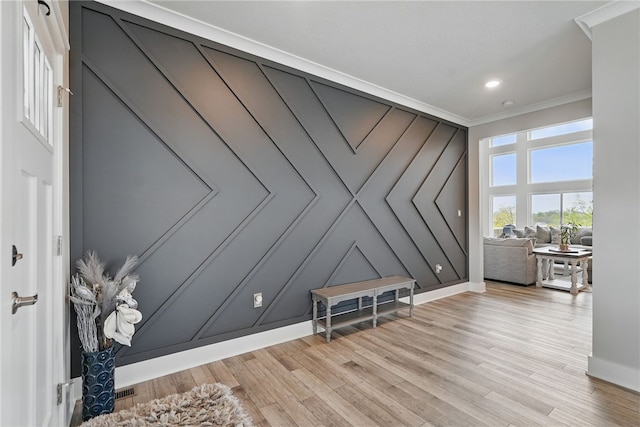 living area with crown molding, light wood-type flooring, baseboards, a decorative wall, and recessed lighting