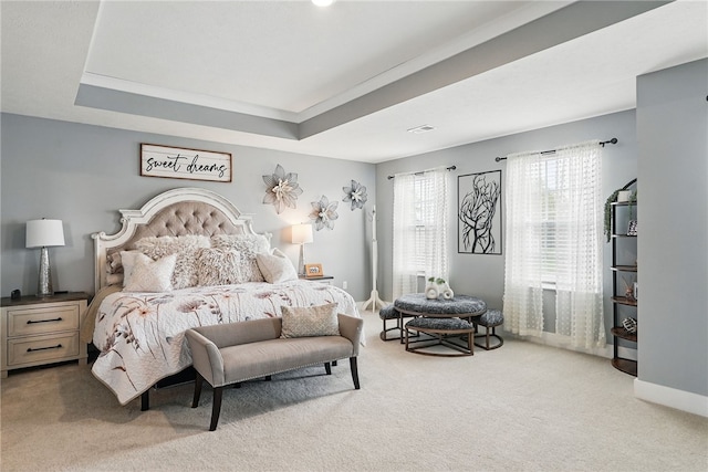 bedroom with light carpet and a raised ceiling