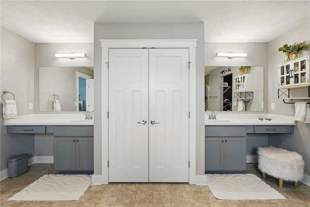 full bath with two vanities, baseboards, and tile patterned flooring