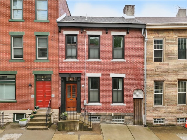 view of front of house with brick siding and a chimney