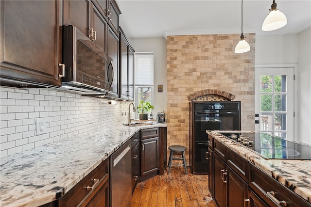 kitchen featuring a sink, black electric cooktop, dark brown cabinetry, and light stone countertops