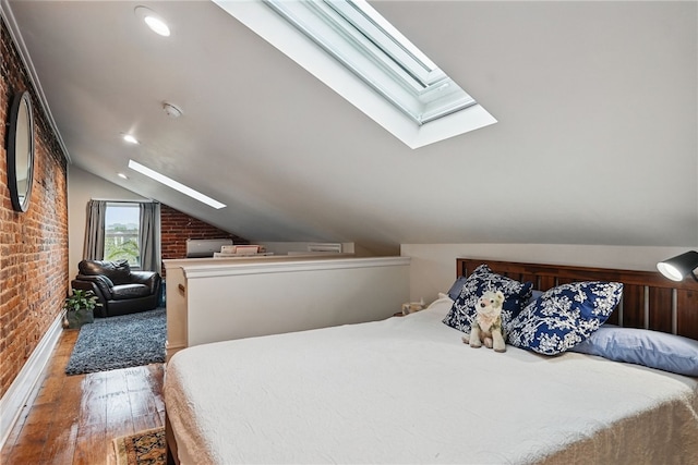 bedroom featuring a skylight, brick wall, wood finished floors, and lofted ceiling