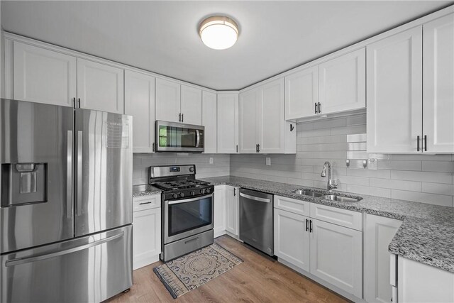 kitchen with stainless steel appliances, a sink, and white cabinets