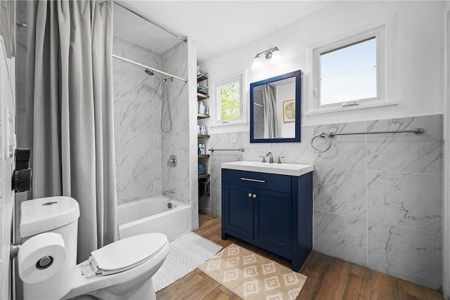 full bath with tile walls, toilet, shower / bathtub combination with curtain, wood finished floors, and vanity