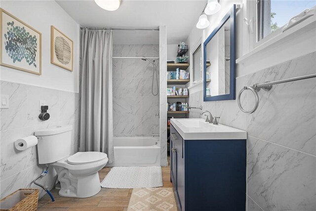 bathroom featuring tile walls, toilet, shower / tub combo with curtain, vanity, and wood finished floors
