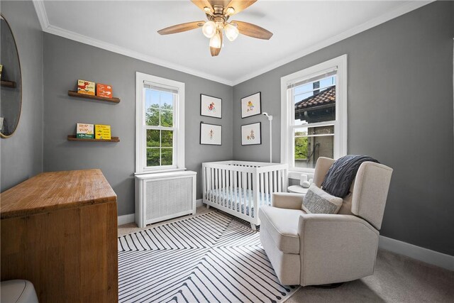 bedroom featuring radiator, baseboards, light colored carpet, ornamental molding, and a crib
