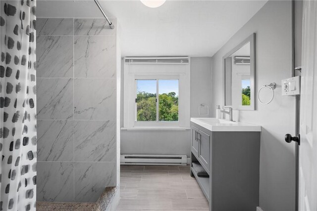full bath featuring baseboard heating, a tile shower, healthy amount of natural light, and vanity