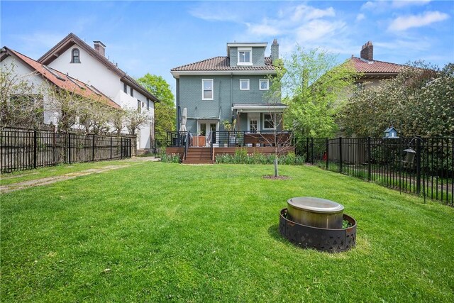 rear view of property featuring a wooden deck and a fire pit