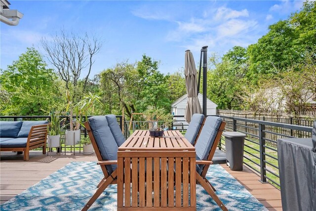 deck featuring a fenced backyard, a storage shed, an outdoor structure, outdoor dining space, and view of scattered trees