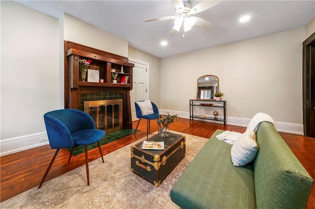 living area with a tile fireplace, wood finished floors, baseboards, a ceiling fan, and recessed lighting
