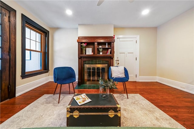 living area featuring a tile fireplace, baseboards, wood finished floors, and recessed lighting